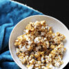 A bowl of Caramel Popcorn atop a blue plush blanket.