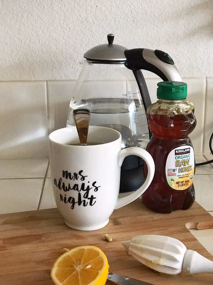A cup of tea on a counter by a bottle of honey.