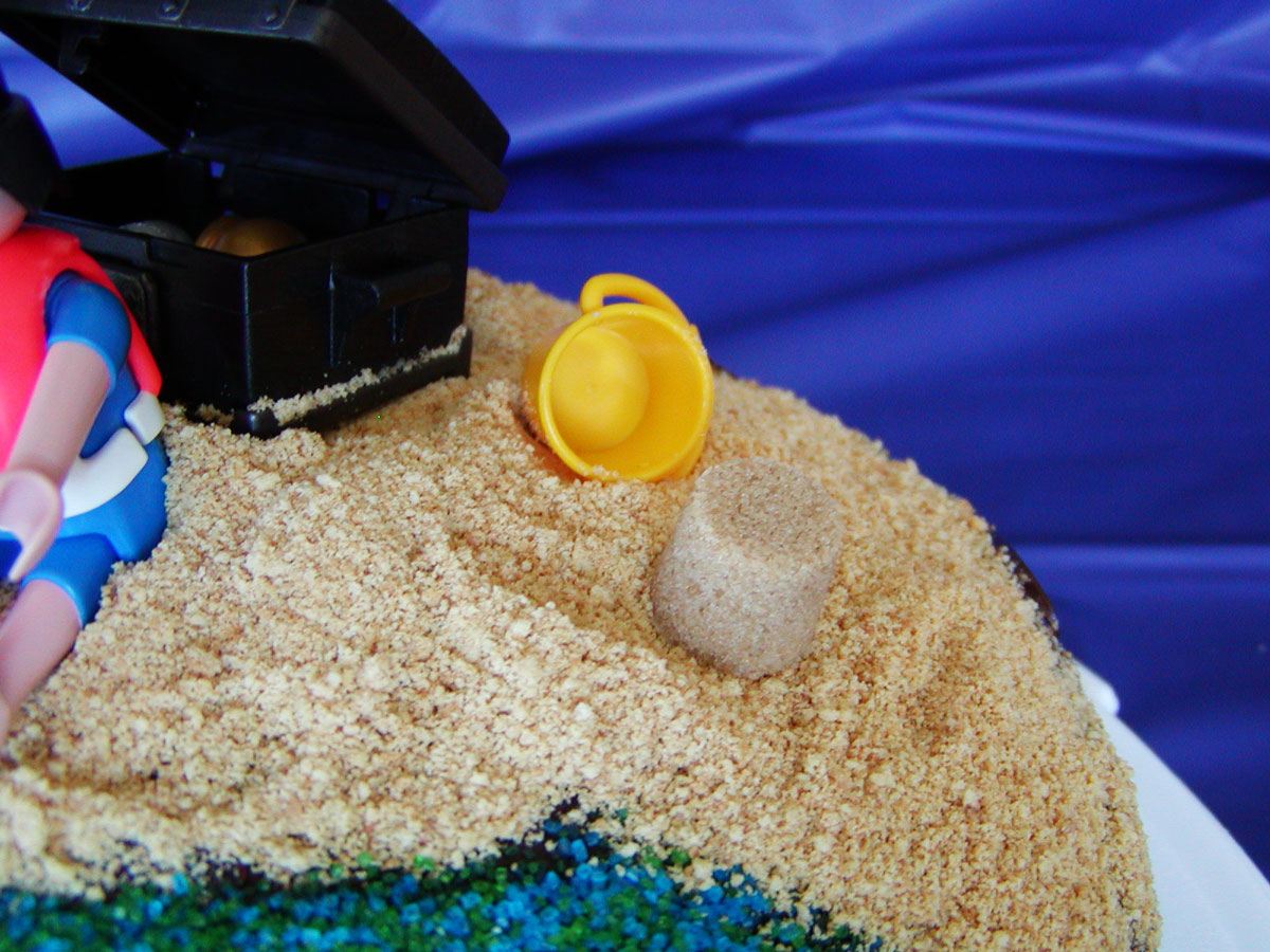 brown sugar sand castle on cake next to toy bucket.