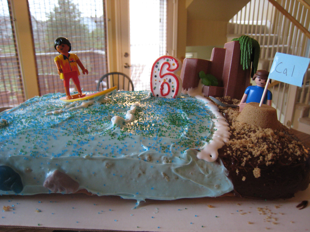 beach cake on kitchen table with number 6 candle inserted.