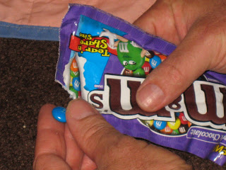 A close-up of hands holding M&M's in package.