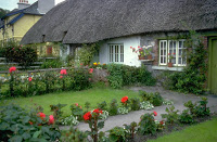 A cottage with grass and flowers.