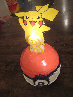 A Paper Pokemon stuck into a poke ball cake with a number 8 candle.