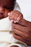 A close up of a baby holding a parent\'s finger.
