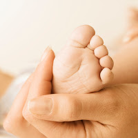 A mom holding her baby\'s foot in her hand.