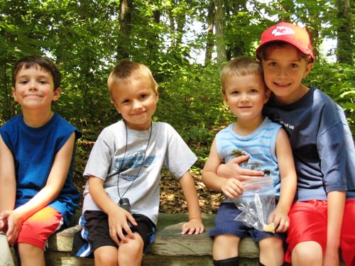 Four boys sitting on a bench posing for the camera.