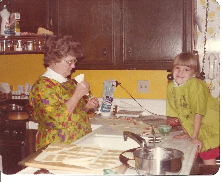 Vintage image of Gramma decorating cookies at counter while granddaughter looks on.