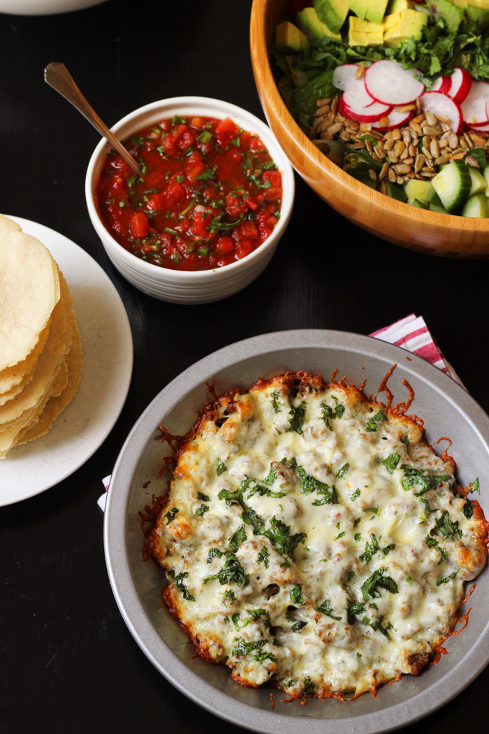 A plate of Queso Fundido with salad and tortillas