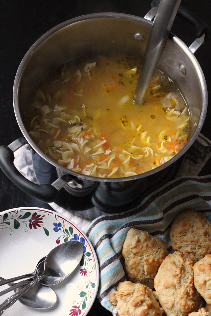 pot of Chicken Noodle Soup with bowls and biscuits