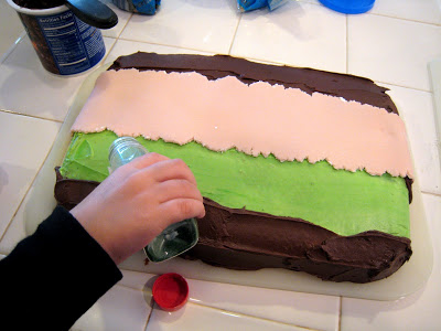 Decorating the bob the builder cake with green sprinkles.