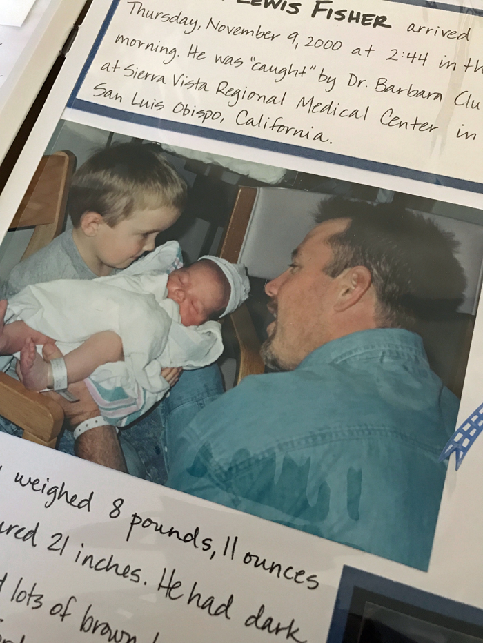 a shot of a scrapbook page with image of dad, boy, and new baby.