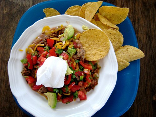 A plate of chips and nacho toppings