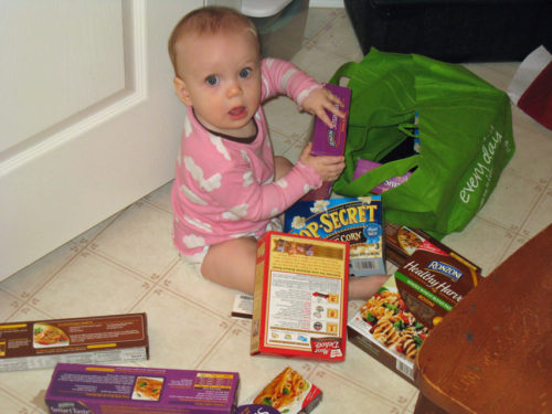 baby on kitchen floor emptying grocery bags.