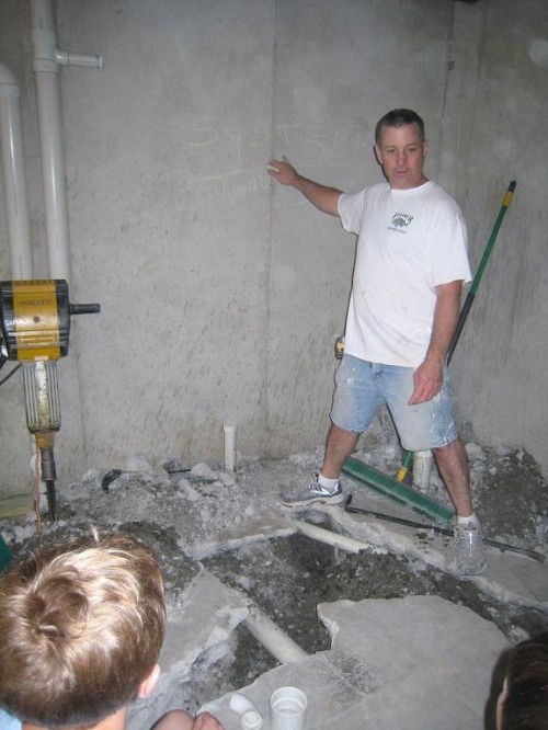 Dad in a basement under construction, explaining to boys the work.