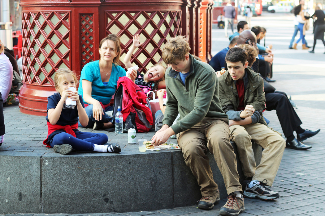 Family picnicking on a bench in London.