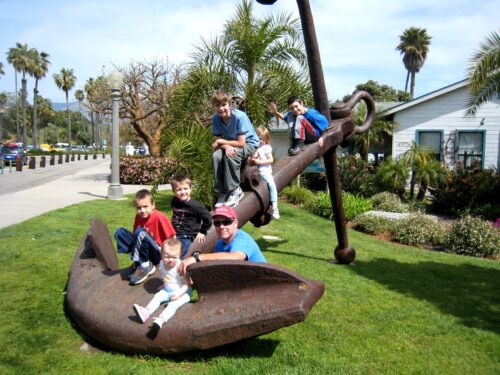 Kids and dad posing by a large anchor at the Maritime Museum in Santa Barbara.