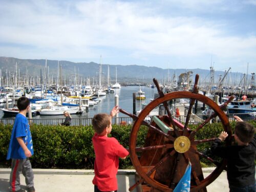 A little boy standing in front of a pier at Maritime Museum in Santa Barbara.