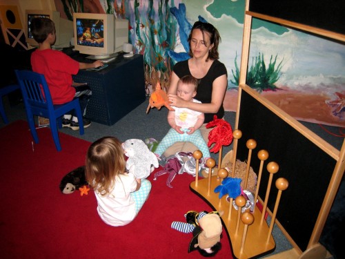 Mom playing with girls in toddler area of Maritime Museum in Santa Barbara.