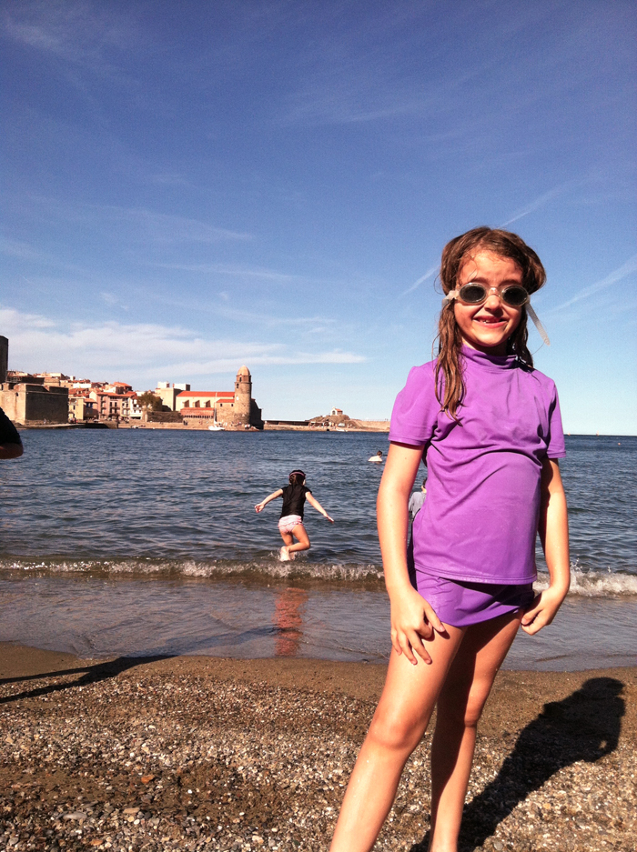 A young girl standing next to a body of water.