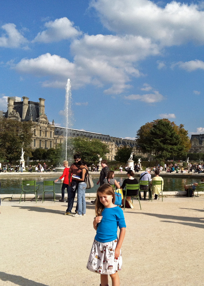 A group of people in Tuileries, with girl in blue shirt looking at the camera.