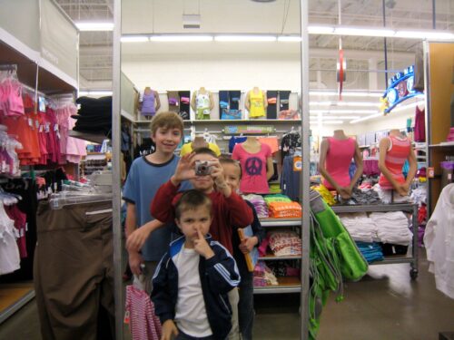 Four boys standing in front of a mirror at Old Navy, goofing off.