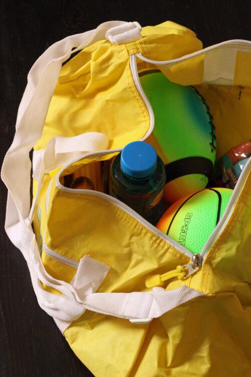 A yellow bag sitting on top of a table full of sports equipment.