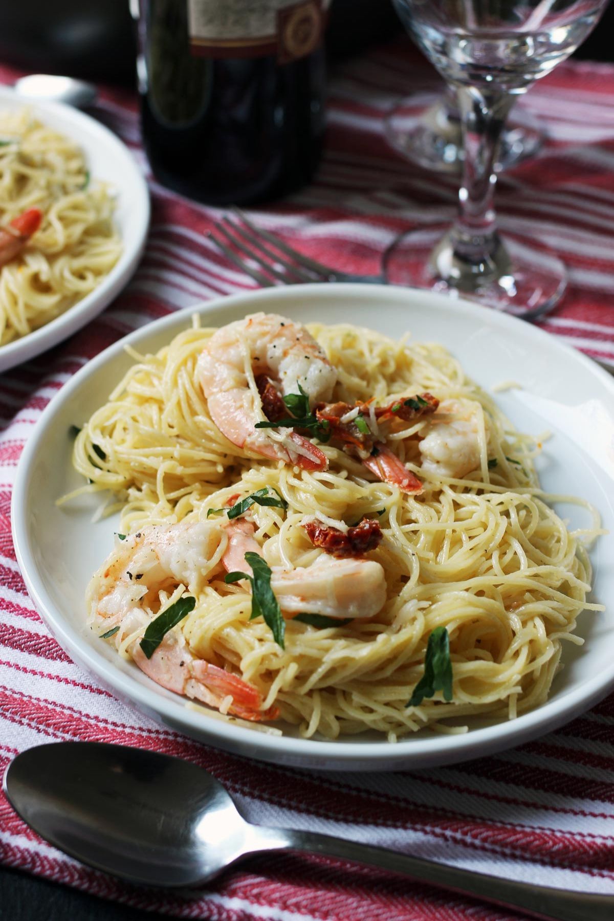 plate of shrimp with pasta on a red cloth with wine glasses.