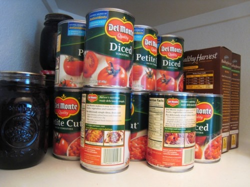 Cans of diced tomatoes on shelf in pantry.