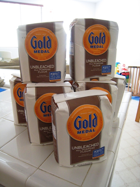 A stack of bagged flour on a counter.