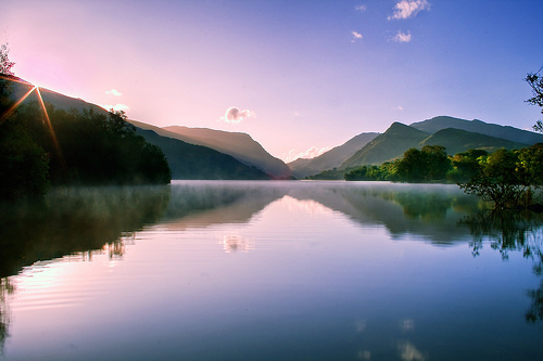 A sunset over a body of water with a mountain in the background