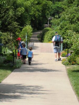 A dad and kids walking down a path in the arboretum.