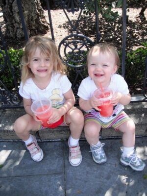 Girls drinking pink lemonade on curb at Disneyland.