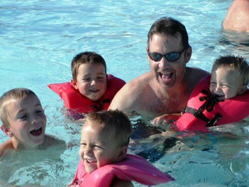 Four brothers with their dad in the pool.