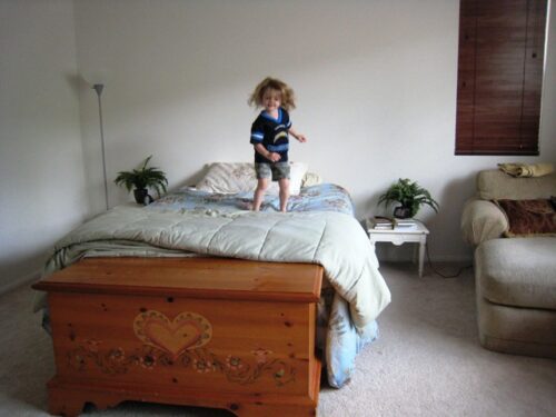 A little girl jumping on a bed.