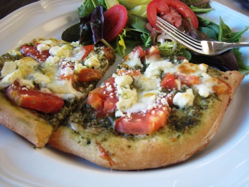 A pizza with Feta and Pesto sitting on a plate