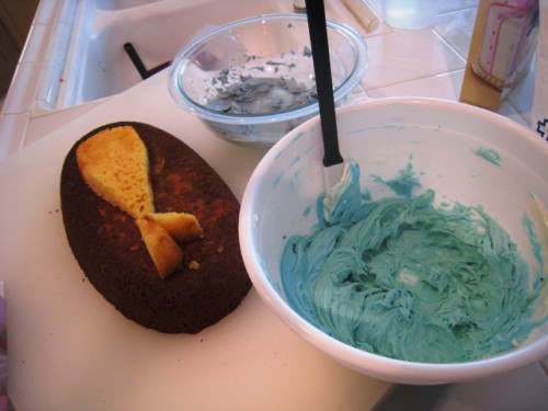 Bowls of frosting next to cakes ready to be frosted like a whale.