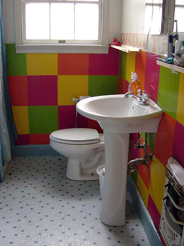A colorful bathroom with a sink and a window and toilet.