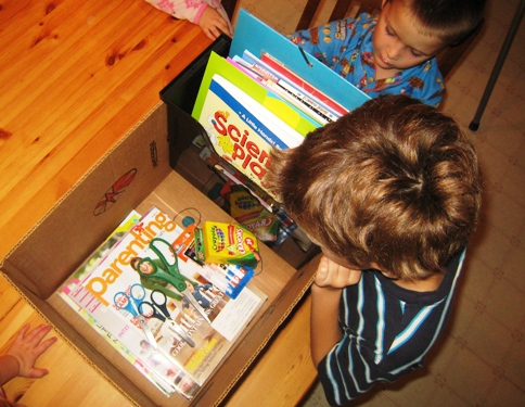 Boys looking into a box of craft books and supplies.