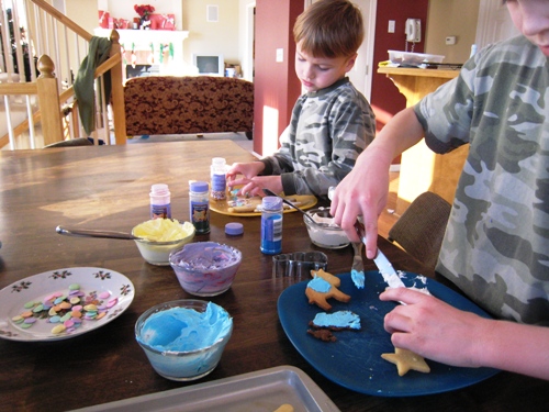 Boys decorating Christmas cookies on kitchen table.