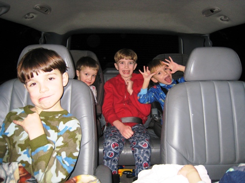 A group of boys sitting in a car posing for the camera with goofy faces.