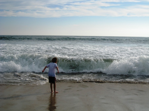 A boy playing in the waves at the beach.