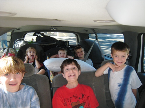 A group of kids sitting in an SUV posing for the camera.