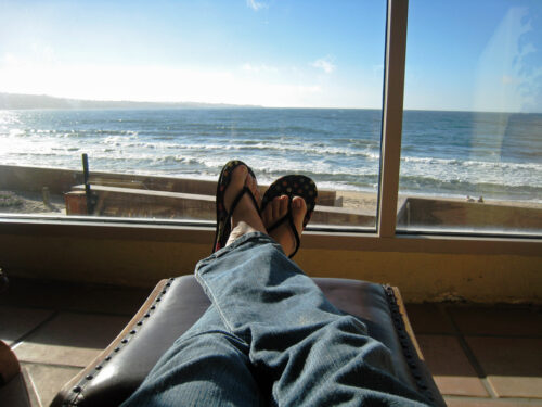 Woman's feet crossed on lounge chair in front of the ocean.