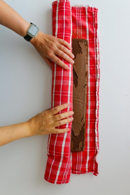 hands rolling cake up in towel.