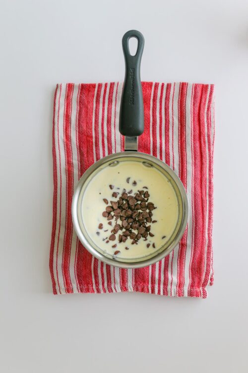 hot cream and chocolate chips in a saucepan on a towel off heat.