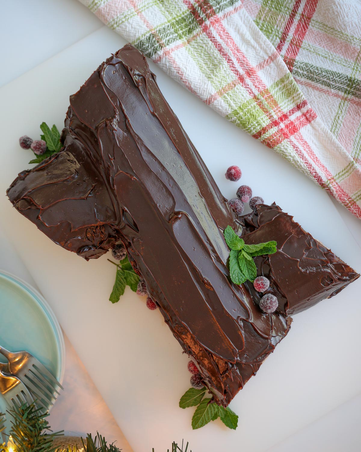 finished buche de noel on white board with plaid cloth and plates and forks.