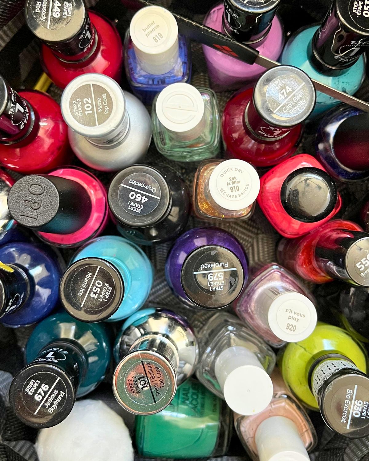 assortment of nail polish bottles in a black basket.