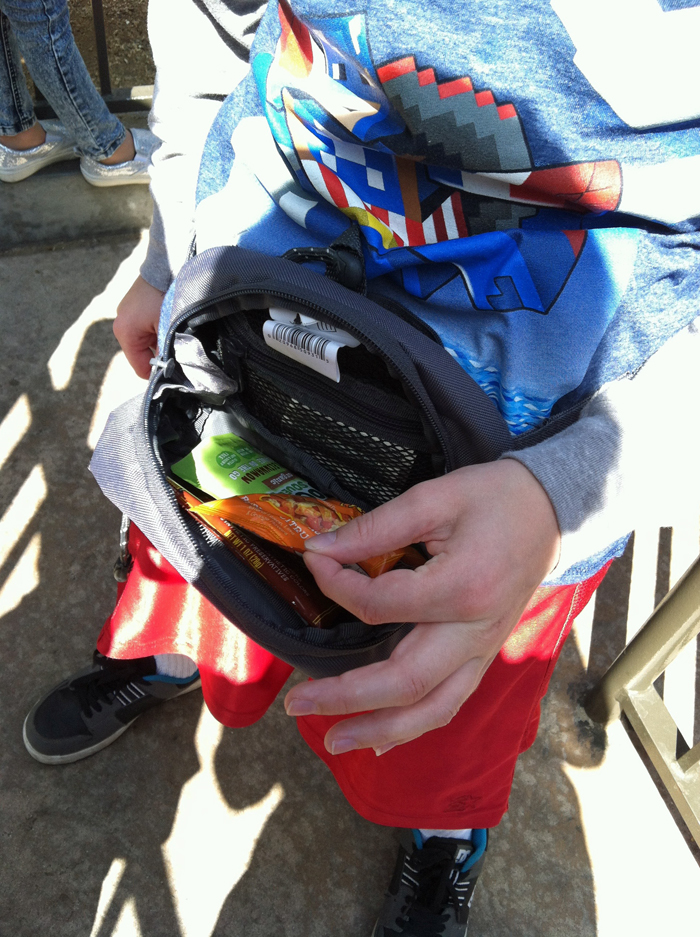 child pulling snacks out of fanny pack.