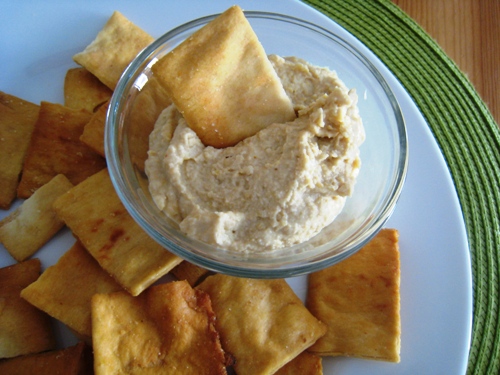 a bowl of hummus on a plate of chips