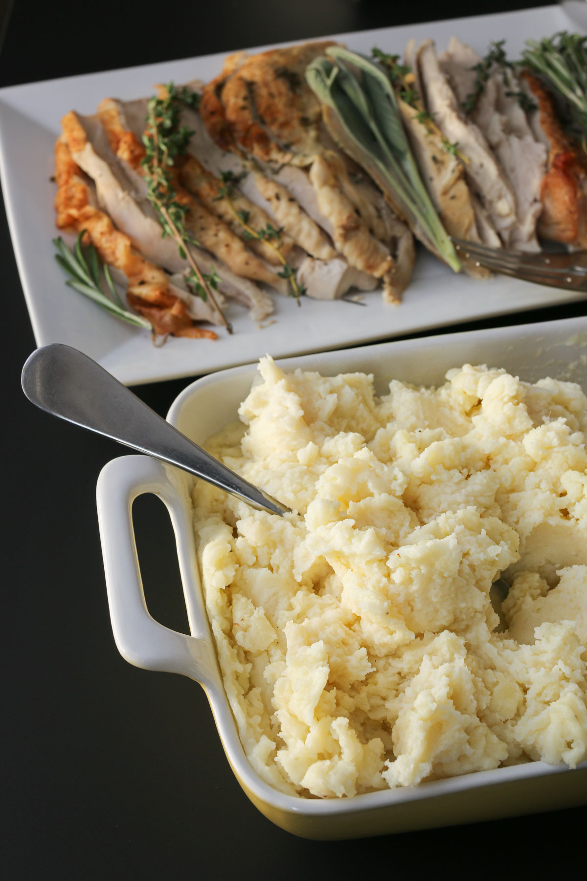 casserole of mashed potatoes next to platter of roast turkey breast.